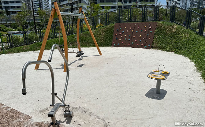 Sand play area with swings and a rock wall